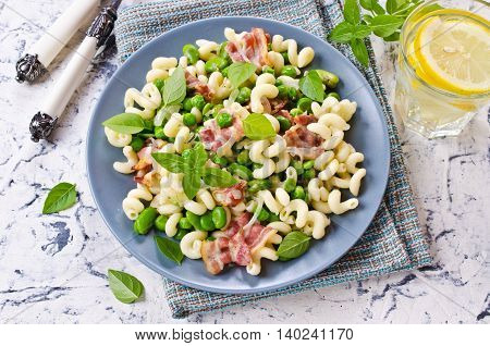 Pasta with bacon and vegetables in portion plate. Selective focus.