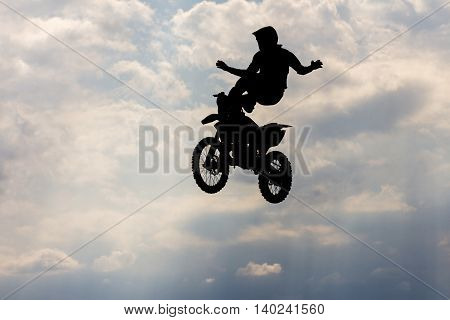 Jumping motorcircle rider silhouette on sky background.
