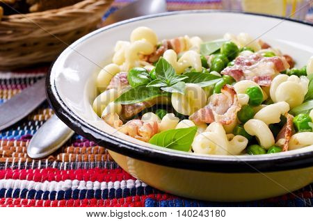 Pasta with bacon and vegetables in portion plate. Selective focus.