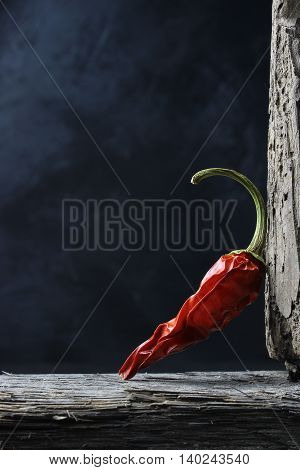 dried chili peppers on wood against a dark background