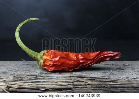 dried chili peppers on wood against a dark background