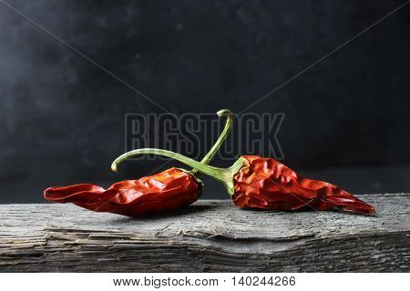 dried chili peppers on wood against a dark background