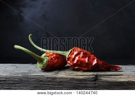 dried chili peppers on wood against a dark background