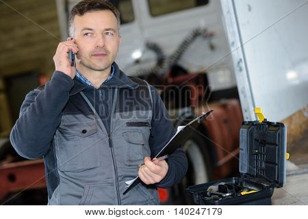 pleasant professional deliveryman holding mobile phone