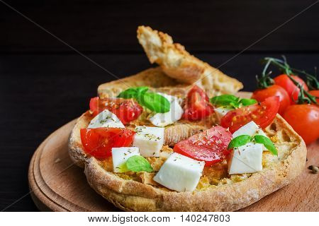 Classical frisella tomato cheese mozzarella and basil. Italian starter friselle. Dried bread called freselle on wooden board. Italian food. Healthy vegetarian food. Antipasti. Selective focus.