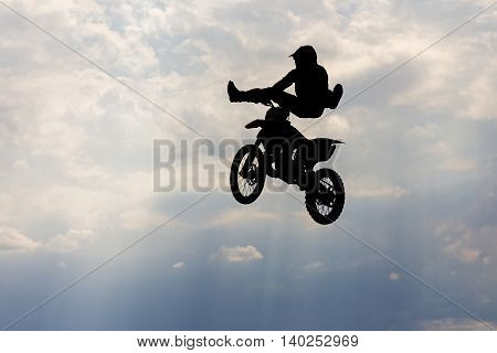 Jumping motorcircle rider silhouette on sky background.