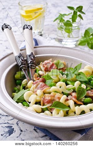 Pasta with bacon and vegetables in portion plate. Selective focus.