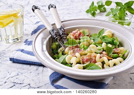 Pasta with bacon and vegetables in portion plate. Selective focus.