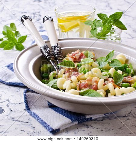 Pasta with bacon and vegetables in portion plate. Selective focus.