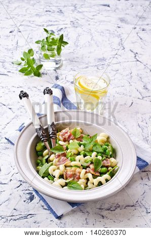 Pasta with bacon and vegetables in portion plate. Selective focus.