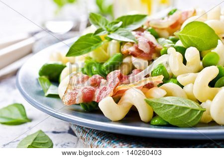 Pasta with bacon and vegetables in portion plate. Selective focus.