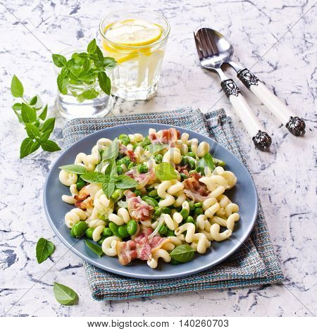 Pasta with bacon and vegetables in portion plate. Selective focus.