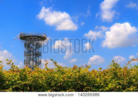 Metal tower on garden with blue sky.