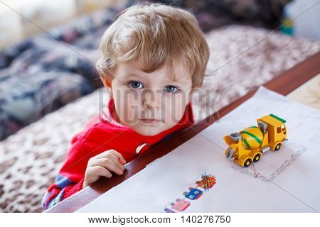 Little toddler boy with blue eyes playing with toy, inddor