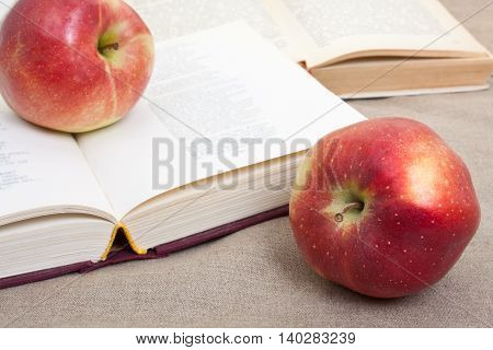 Composition With Red Apples And Opened Books On The Table, On The Decorative Linen Cloth.