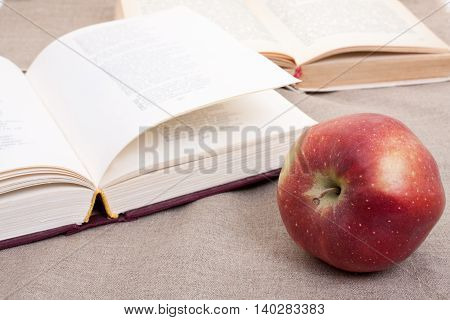 Composition With Red Apple And Opened Books On The Table, On The Decorative Linen Cloth.