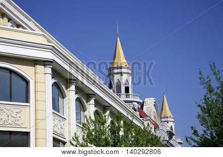 The exterior of a building with a gold roof on Zhongyang street in harbin China located in Heilongjiang province on a sunny blue sky day.