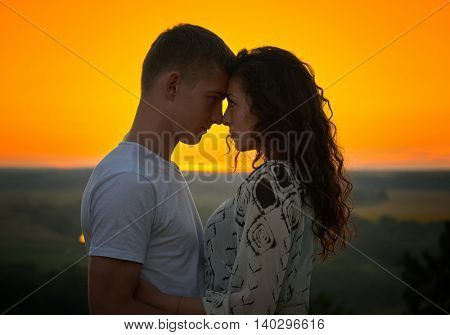 romantic couple at sunset on bright yellow sky background, love tenderness concept, young adult people