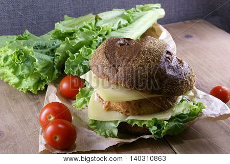 Picnic, sandwich with meat, cheese and fresh vegetables is lying on a rustic wooden table