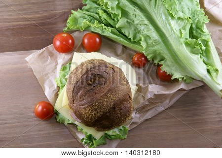 Picnic, sandwich with meat, cheese and fresh vegetables is lying on a rustic wooden table. Top view