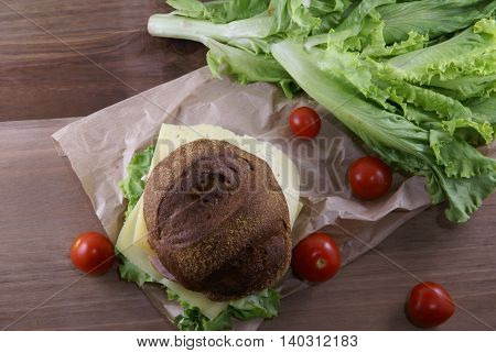 Picnic, sandwich with meat, cheese and fresh vegetables is lying on a rustic wooden table. Top view