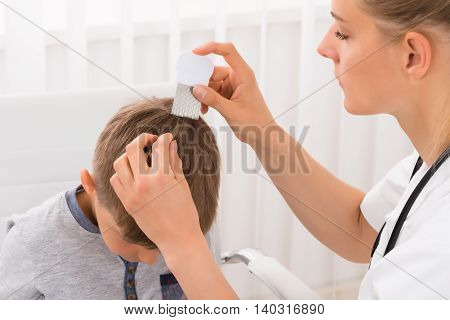 Close-up Of Female Doctor Doing Treatment On Boy's Hair With Comb
