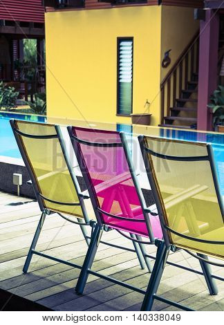 three deck chairs by the side of a pool 