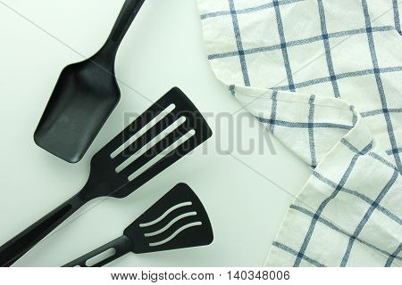 black ladle and spade of frying pan on the white table