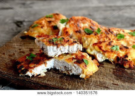 Turkey meat pieces fried in batter and garnished with parsley leaves. Cut Turkey cutlets on a cutting board and an old wooden background. Delicious poultry recipe