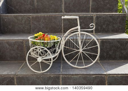 Vintage decorative metal bicycle flower-stand with flowers on stairs of a house