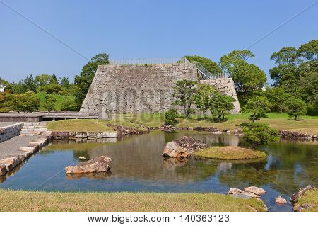 AKO JAPAN - JULY 18 2016: Pond and stone base of main keep (donjon or Tenshu) in main bailey of Ako Castle (circa 17th c.) in Ako Japan. Castle was a seat of Lord Asano Naganao