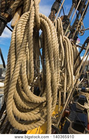 Closeup of rolled thick ropes on the old ship near wooden cleats