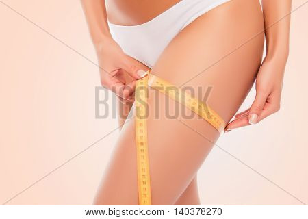 Close Up Photo Of Sexy Woman Measuring Her Leg's Size With Tape Measure