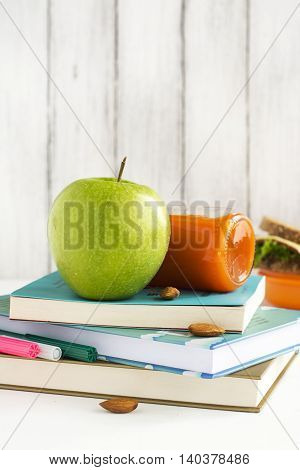 School lunchbox: healthy food, fruits, books and apple over white table. Selective focus