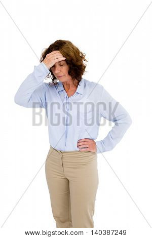 Mature woman touching head while standing against white background