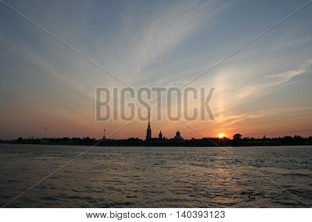 Towers and pillars of fortress and sunset on Neva river