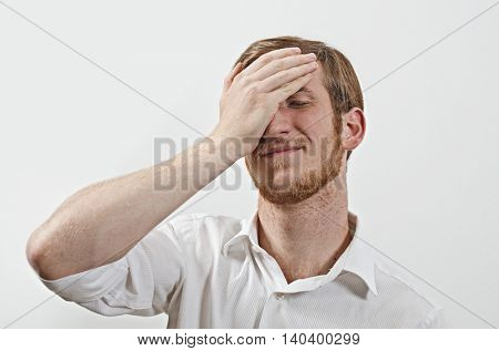 Young Adult Male Wearing White Shirt  Covers His Face by Hand, Gesturing He Has Made a Big Mistake