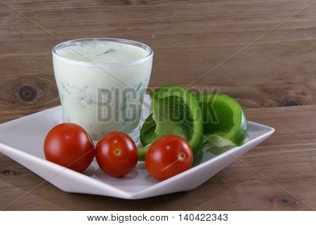 Useful summer snack: vegetables and yogurt sauce with herbs. Against the background of a rustic wooden table