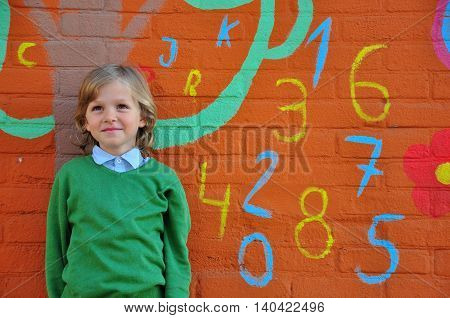 Little smiling boy at the school wall