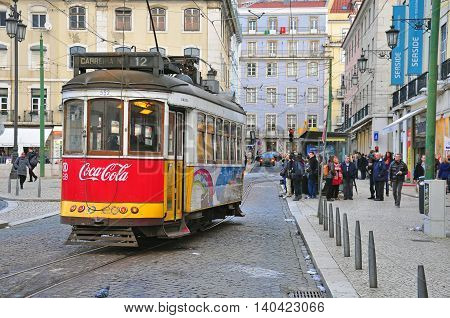 LISBON PORTUGAL - NOVEMBER 27: Red tram number 12 goes by the street of Lisbon city center on November 27 2013. Lisbon is a capital and must famous city of Portugal
