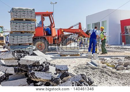 Zrenjanin Vojvodina Serbia - September 14 2015: Workers are helping forklift to place on right place plate compactor machine.