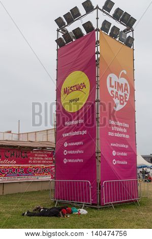 Lima, Peru - September 11, 2015: People sleeping in front of a Mistura Festival sign post