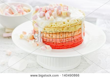 Pink rainbow pancakes with marshmallow sauce for breakfast or dessert selective focus