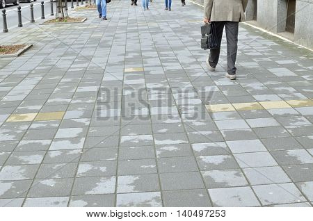 Passersby on a pavement in city center during day