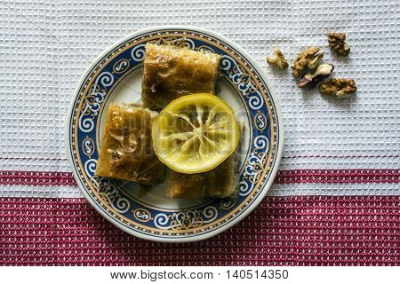 Baklava dessert decorated with lemon slice and walnuts. Top view.