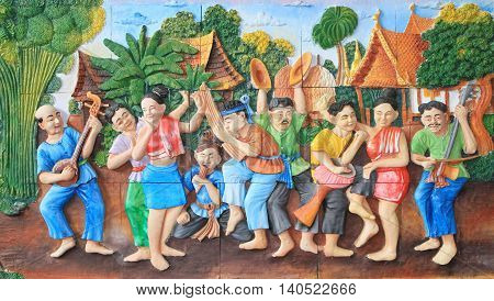 Stone carving and painting of traditional Thai musical instrument and Thai dance on temple wall