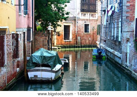 A typical small street in Venice with two boats docked and drying clothes