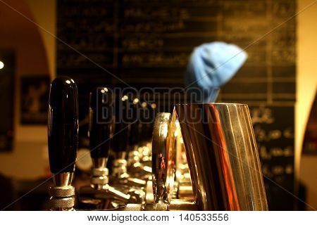 A close view of golden beer taps with black handles and a blue cap at the background