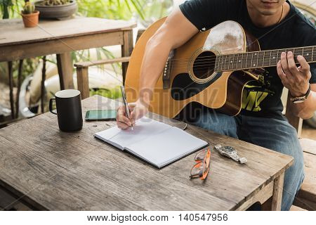 man compose song and play guitar on wood table