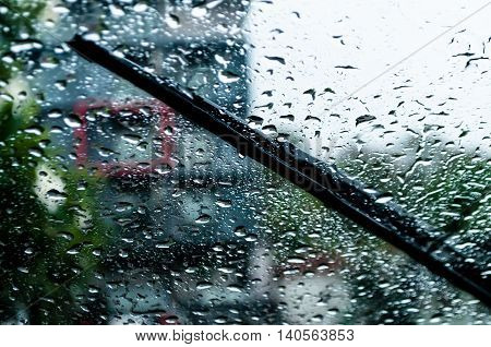 raindrops and wiper on car windshield. use wipers and drive slowly in the rain for safety.